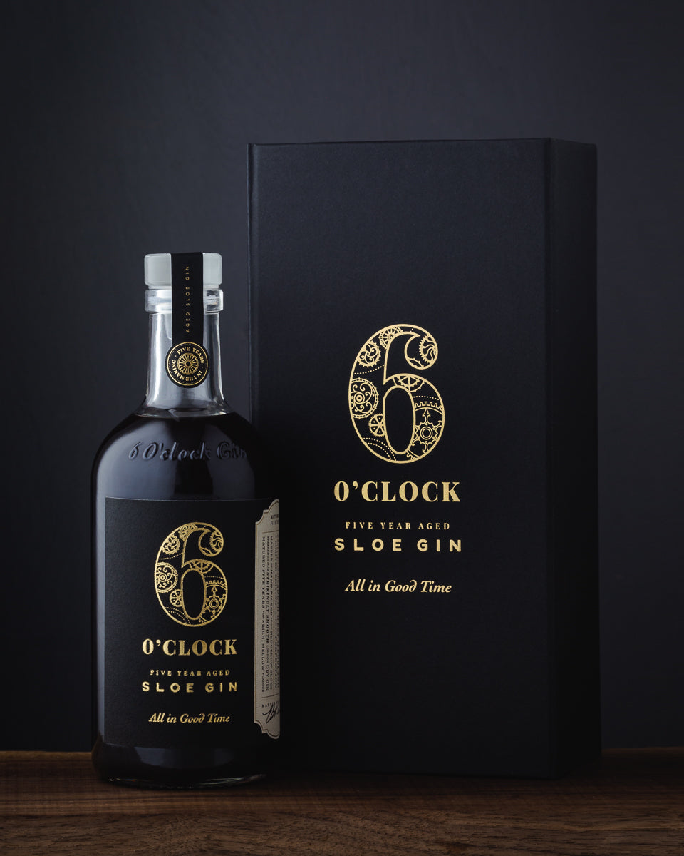Bottle and box of 6 O'Clock Aged Sloe Gin on a dark background